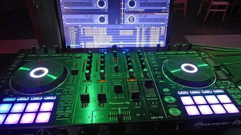 Pioneer DJ controller lit up next to a laptop running DJ software, a typical first setup for a techno DJ Pioneer DJ controller lit up next to a laptop running DJ software, a typical first setup for a techno DJ