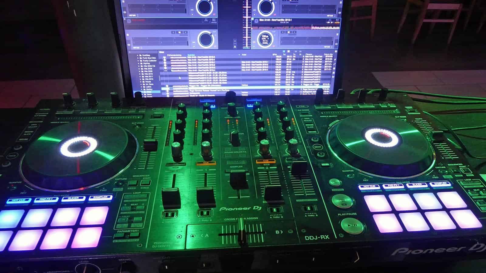 Pioneer DJ controller lit up next to a laptop running DJ software, a typical first setup for a techno DJ Pioneer DJ controller lit up next to a laptop running DJ software, a typical first setup for a techno DJ