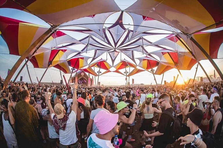 Crowd dancing under the psychedelic mandala canopy at Monegros Desert Festival in the Fraga desert