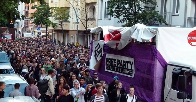 Crowd and a purple sound-system truck at the Fuckparade in Berlin, with a Free Party Is Not A Crime banner Crowd and a purple sound-system truck at the Fuckparade in Berlin, with a Free Party Is Not A Crime banner