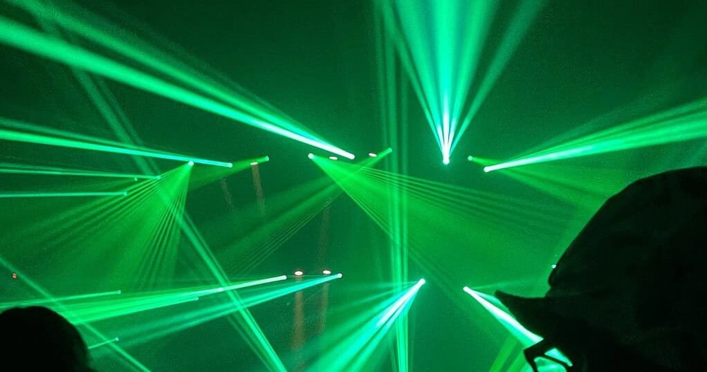 Green laser beams over a hard techno rave crowd