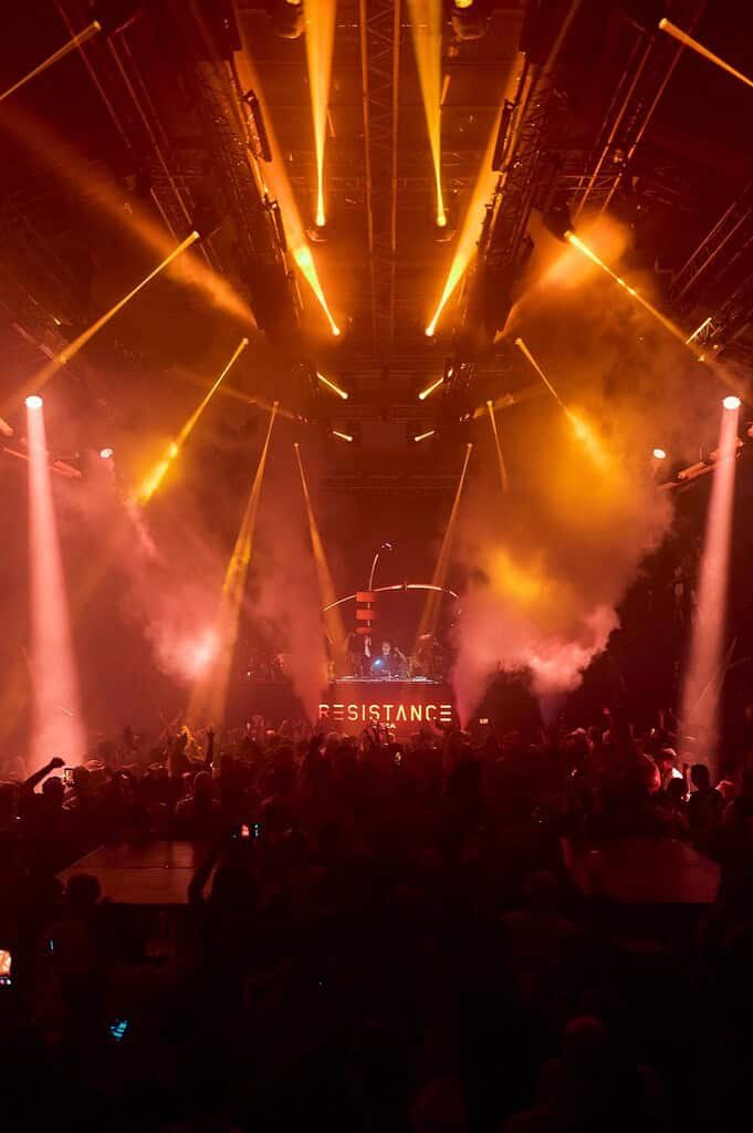 RESISTANCE illuminated booth and orange lasers over the crowd at Amnesia during the 2026 opening party RESISTANCE illuminated booth and orange lasers over the crowd at Amnesia during the 2026 opening party