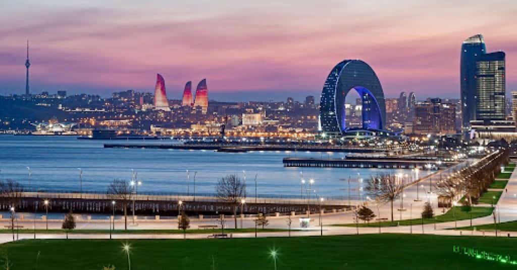 Baku Boulevard and the Caspian Sea waterfront at dusk with the Flame Towers lit above the city