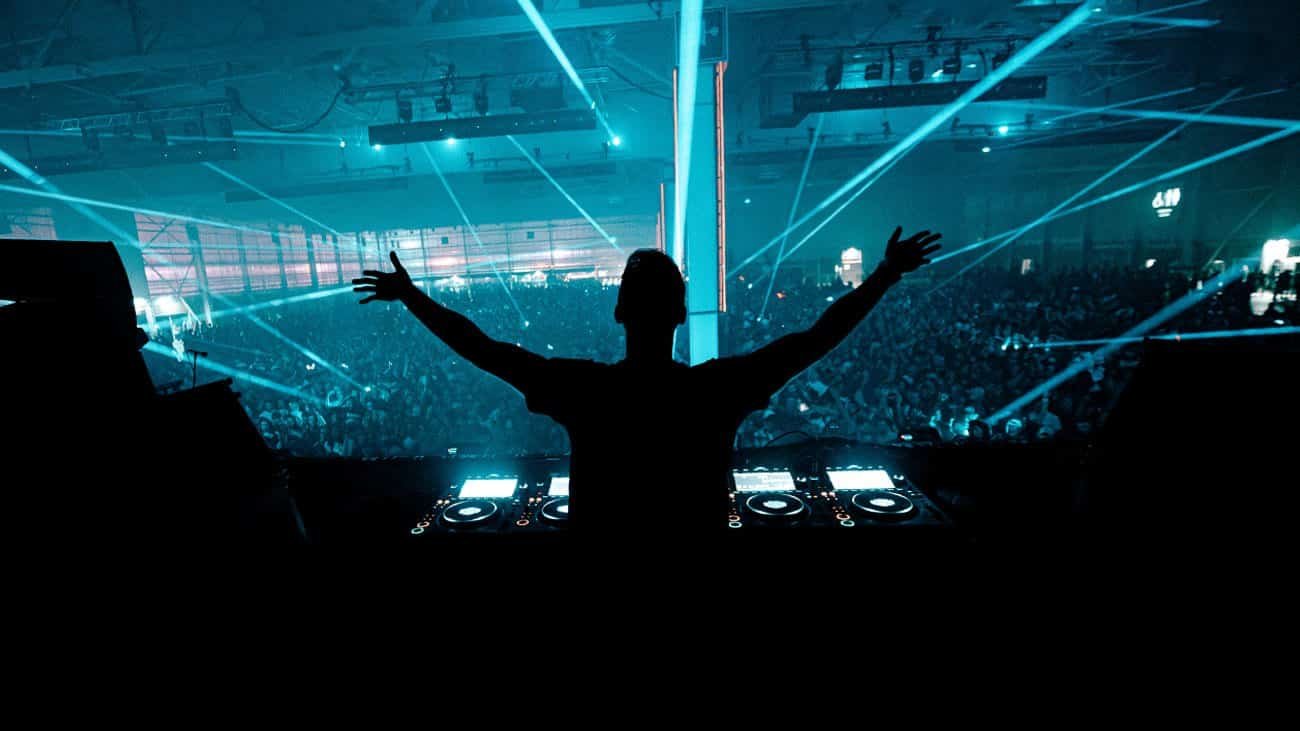 DJ with arms raised over the Dream Nation crowd and cyan lasers at Parc des Expositions Paris Nord Villepinte