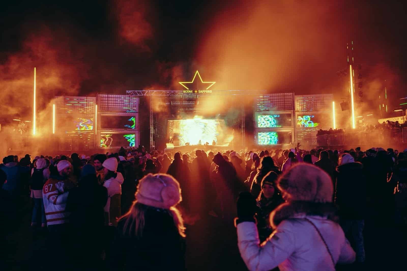 Igloofest crowd in winter gear at the Sapporo Stage, Montreal Old Port Igloofest crowd in snowsuits and toques facing the Sapporo Stage at night in Montreal's Old Port