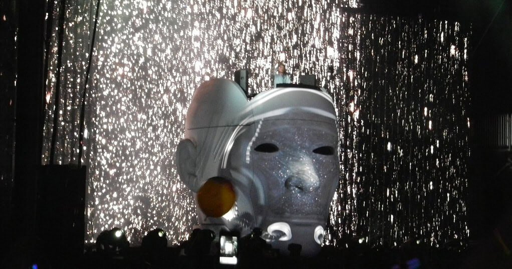 Avicii performing Levels inside a giant illuminated head under a curtain of sparks at Lollapalooza 2012