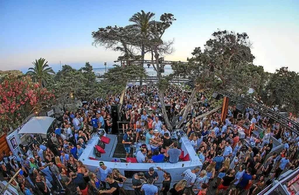 The Best Beach Clubs in Europe for 2027 2 Crowd around the circular bar at Blue Marlin Ibiza in Cala Jondal at sunset