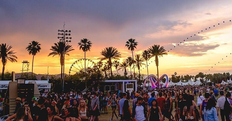 Coachella festival at sunset with the Ferris wheel, palm trees and crowd on the Empire Polo Club grounds Coachella festival at sunset with the Ferris wheel, palm trees and crowd on the Empire Polo Club grounds