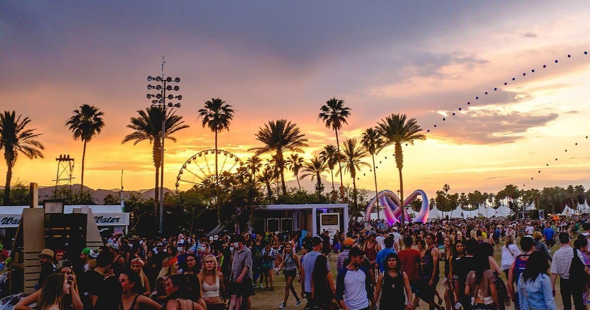 Coachella festival at sunset with the Ferris wheel, palm trees and crowd on the Empire Polo Club grounds