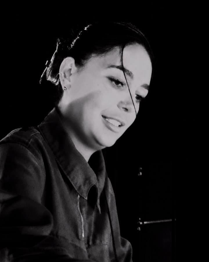Highest-Paid Female Techno DJs 2026: Amelie Lens, Charlotte de Witte and 12 More 12 Hannah Laing smiling on stage at Doof in the Park 2026 in Dundee, black and white