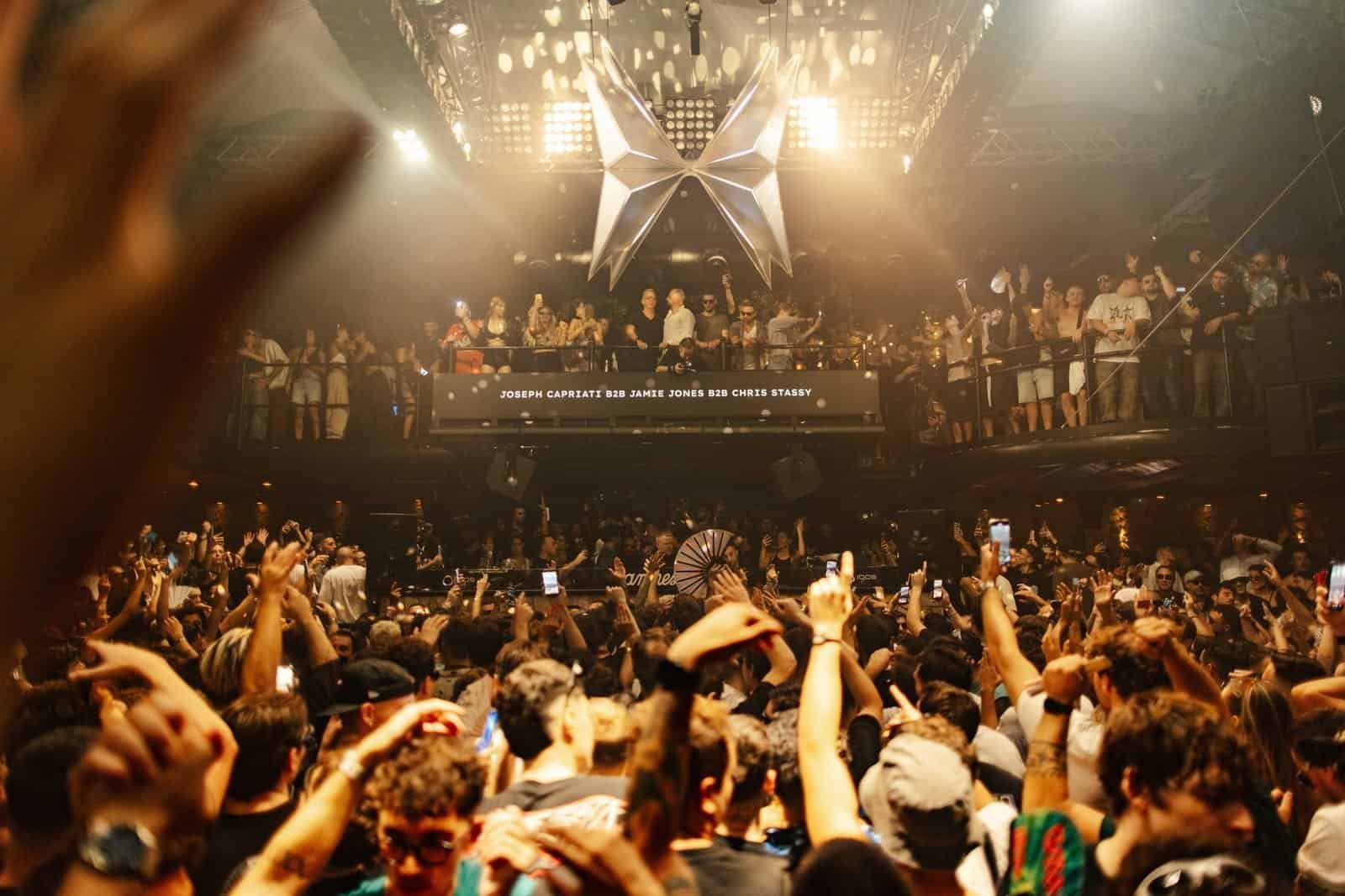 Packed Amnesia Ibiza terrace with the DJ booth screen reading Joseph Capriati B2B Jamie Jones B2B Chris Stassy at the Metamorfosi closing party