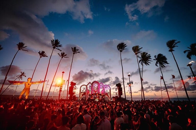 Crowd under palm trees at the Réveillon Carneiros beach stage at sunset in Pernambuco, Brazil Crowd under palm trees at the Réveillon Carneiros beach stage at sunset in Pernambuco, Brazil