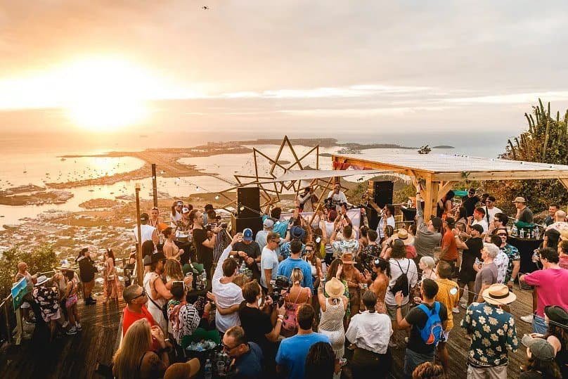 Nine Destination Festivals Worth Travelling For in 2026 and 2027 5 Sunset party on a hilltop terrace overlooking the sea at SXM Festival, Saint Martin
