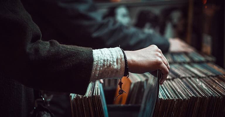 Hand flipping through vinyl records in a record shop crate, the home of tech house record labels