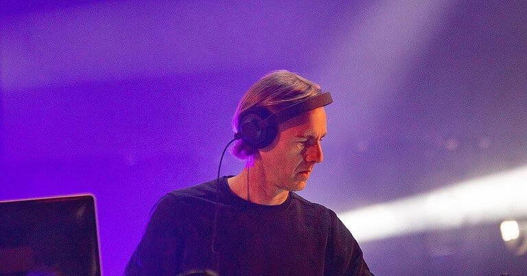 Richie Hawtin playing a live techno set in purple stage light at SonneMondSterne festival, one of the techno artists every beginner should know Richie Hawtin playing a live techno set in purple stage light at SonneMondSterne festival, one of the techno artists every beginner should know