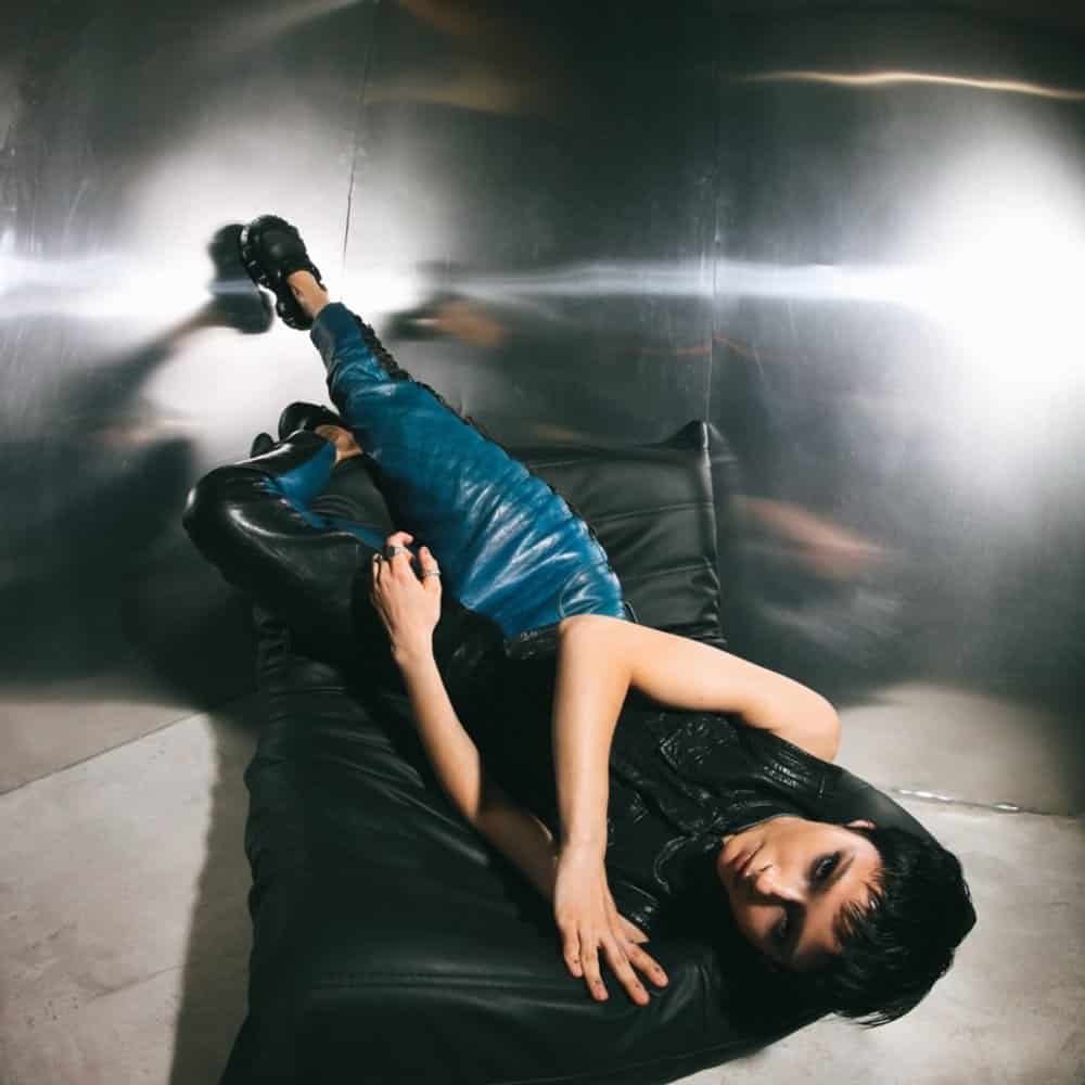 The Aksis Releases Independent Techno Single Quit It After Armada Debut 1 Quit It single cover art by The Aksis, Anna Kuprienko lying on a black leather sofa in a mirrored room